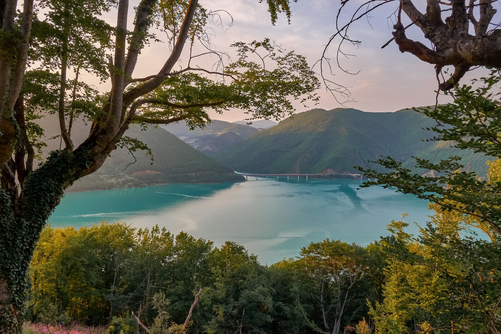 Paisaje de un mar rodeado de colinas con vegetación bajo un cielo nublado